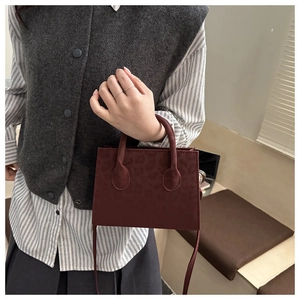 Detail of burgundy leopard embossed mini square bag with handle and slim strap