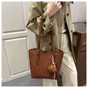 Dettaglio borsa tote vintage marrone con ciondolo a forma di cane e fibbie in metallo