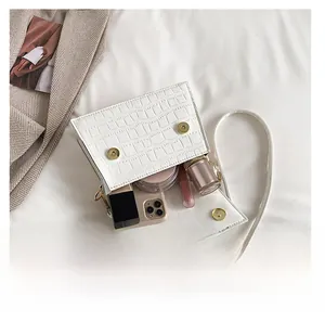 Vue détaillée de l'intérieur du sac blanc à motif crocodile avec maquillage et mobile