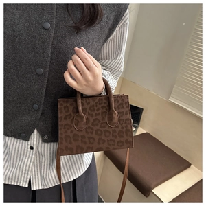 Detail of leopard print crossbody bag showing suede texture and top handle design