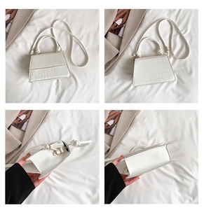 Détails du sac trapèze blanc avec gaufrage croco, finitions dorées et poignée à nœud