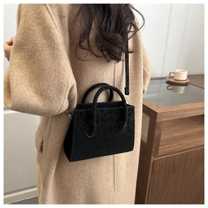 Detail of black leopard print crossbody bag with top handles and shoulder strap