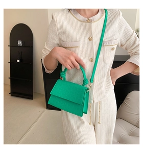 Détail d'un sac à main vert à texture crocodile avec poignée nouée et rabat moderne