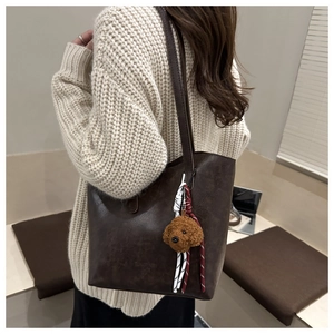 Dettaglio borsa tote vintage in pelle marrone con ciondolo a cane e cinturino intrecciato