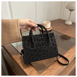 Detail of a chic leopard print bucket bag with gold hardware and detachable strap