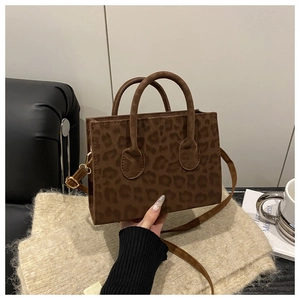 Close-up of leopard print crossbody bag with golden hardware and tote handles