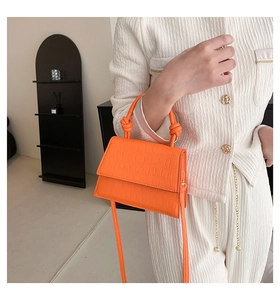 Gros plan du sac à main orange motif crocodile avec poignée nouée et détails soignés