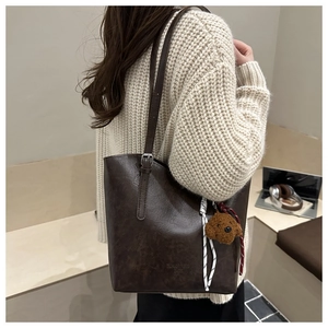 Dettaglio della borsa tote in pelle marrone con ciondolo a forma di orso e fibbia