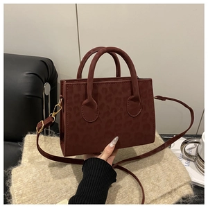 Close-up of wine red leopard print handbag with golden metal hardware and round handles