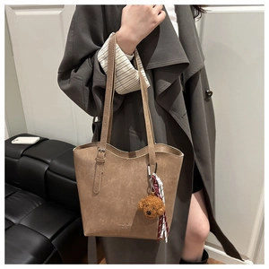 Borsa tote marrone con ciondolo di peluche e sciarpa a quadri indossata a spalla