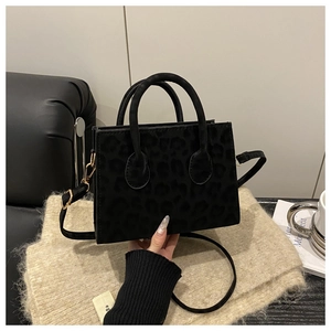 Detailed view of the leopard print suede material and golden hardware on the black handbag