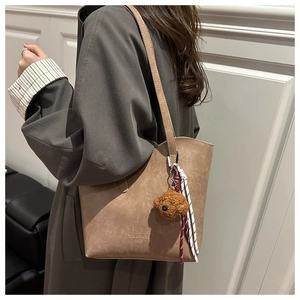 Dettaglio della borsa tote in pelle kaki con ciondolo a orsetto e corda intrecciata