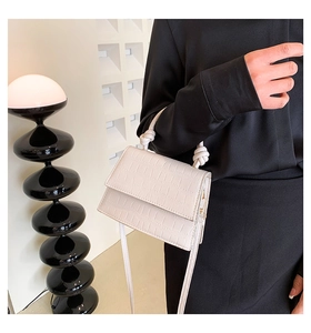 Détail du sac à main crème effet crocodile avec poignée nouée et coutures précises