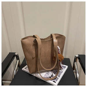 Dettaglio di una borsa tote in ecopelle marrone con ciondolo a orsetto e finitura retrò