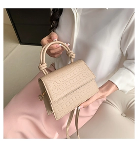 Détail d'un sac à main beige à motif crocodile avec poignée à design noué unique