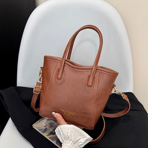 Brown lychee grain bucket bag with gold logo on white chair and black blazer
