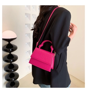Sac à bandoulière rose fuchsia à texture crocodile avec détail de nœud sur le mannequin