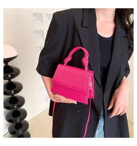Détail d'un mini sac magenta à motif crocodile avec une poignée design à nœud élégante