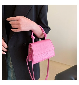 Détail du sac rose effet crocodile avec poignée nouée et finitions métalliques dorées