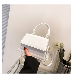 Détail du sac blanc à motif crocodile avec poignée nouée et finitions en métal doré