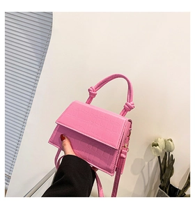 Gros plan du sac à main rose à motif crocodile avec poignée nouée au design unique