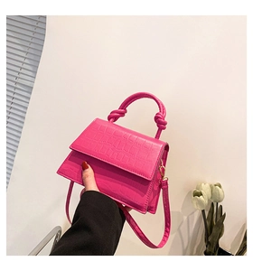 Détail du mini sac fuchsia à motif croco avec poignée nouée et finitions dorées