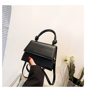 Détail du sac à main noir en cuir gaufré crocodile avec poignée décorative et bandoulière