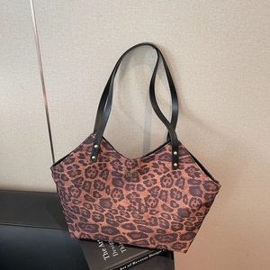 Chic leopard print tote bag with black leather straps on a stylish armchair