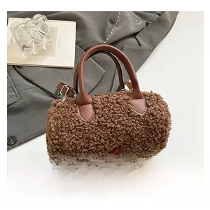 Detail of brown faux shearling cylinder bag with smooth leather handles and long strap