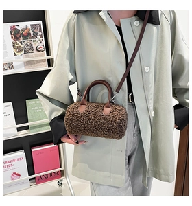 Detailed view of brown shearling barrel bag with leather straps and metallic silver hardware