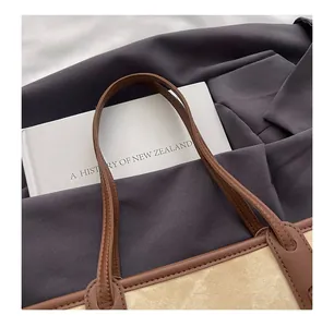 Détail du cabas en toile beige avec sangles en cuir marron et coutures renforcées