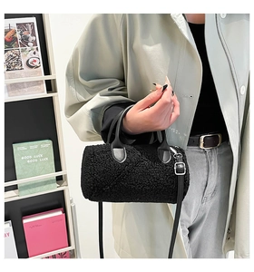 Detail of black lamb wool barrel bag featuring soft plush texture and leather strap