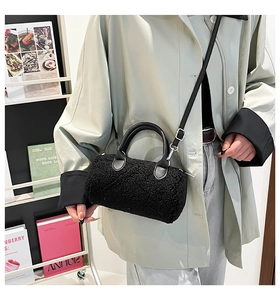Detail of black faux shearling pillow bag with leather handle and silver hardware