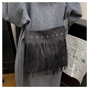 Détail du sac bandoulière en daim noir avec de longues franges et des oillets