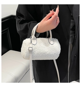 Detail of white faux shearling cylinder bag showing leather handles and metal hardware