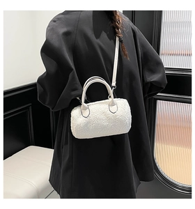 Detail of white plush barrel bag with smooth leather strap worn by a model in black