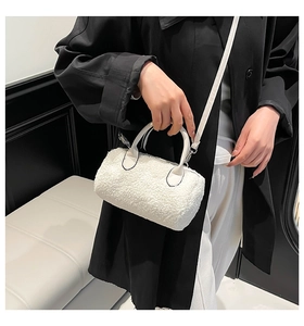 Detail of white faux shearling barrel bag with plush wool texture and metal clasp