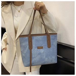 Détail du grand sac cabas en denim avec anses en cuir marron et coutures contrastées