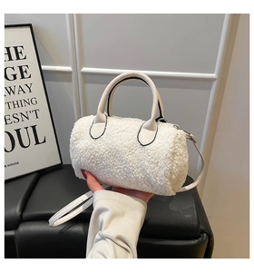 Detail showing plush white faux shearling texture and cream leather strap on pillow bag