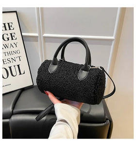 Detail of black faux shearling cylindrical barrel bag with leather straps and silver hardware