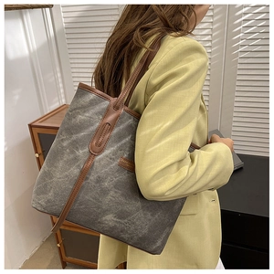 Détail d'un grand sac cabas en toile avec anses en cuir marron et texture marbrée