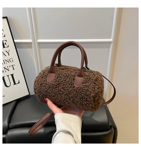 Detail showing the brown faux shearling cylinder bag with leather handles and strap