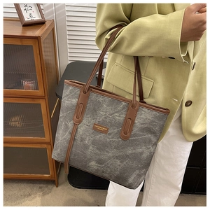 Détail du grand sac cabas en toile grise avec bordures en cuir marron et étiquette