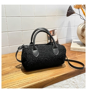 Close-up of black teddy faux fur boston bag with leather handles on a wooden table