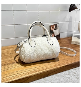 Detail of soft white faux shearling cylinder bag with leather handles and strap