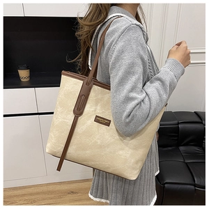 Détail du sac cabas en toile beige avec finitions en cuir marron et fines anses