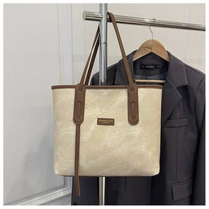 Détail du grand sac cabas en toile avec motif marbre, lanières en cuir et logo