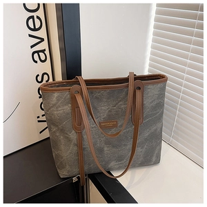 Détail du sac cabas en toile grise avec bordure en cuir marron et étiquette mode