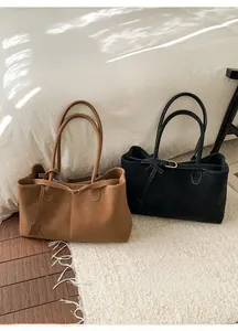 Detail of minimalist black and brown tote bags with metal buckles in a cozy room