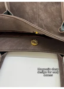 Detail of the magnetic buckle closure on a large brown leather tote bag for easy access